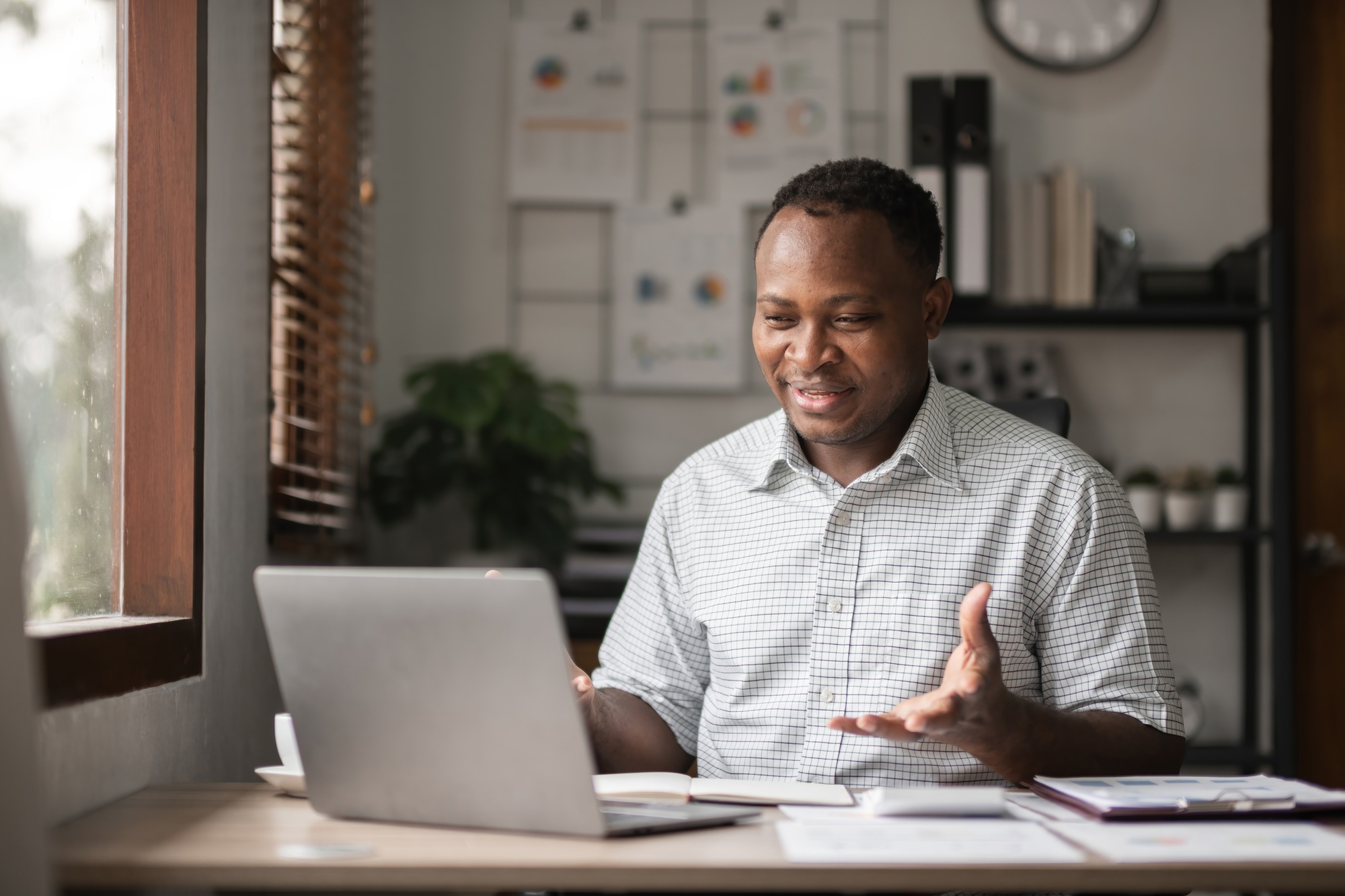 African American businessman working with laptop, online meeting and presenting results via Zoom